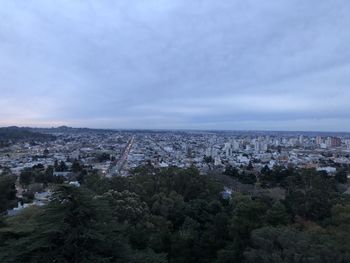 High angle view of city buildings against cloudy sky