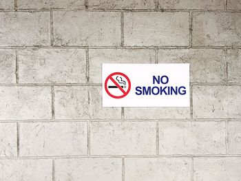 Close-up of road sign against wall