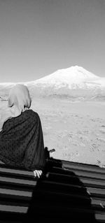 Man standing on snow covered mountain against clear sky