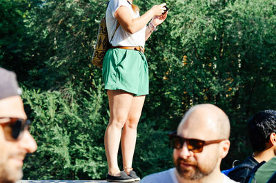 Cropped view of woman standing on wall using smart phone