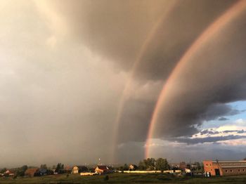Rainbow over city against sky