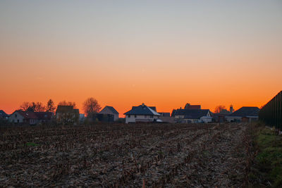 Houses on field against sky during sunset