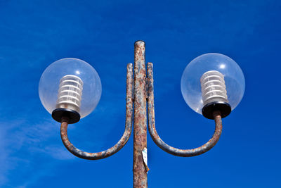 Low angle view of illuminated street light against blue sky