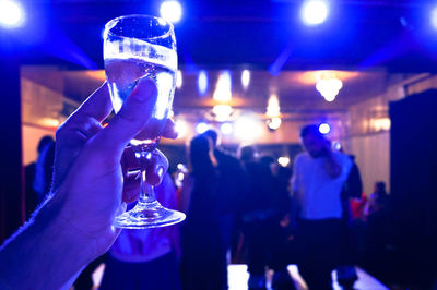 Close-up of hands holding drink during party at night