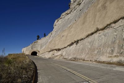 Rock face with layers from the past, but road from the present