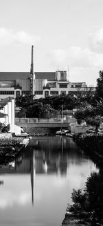 Buildings by river against sky in city