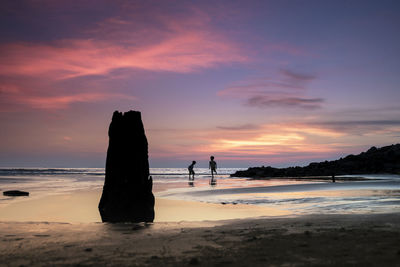 Silhouette people at beach against sky during sunset