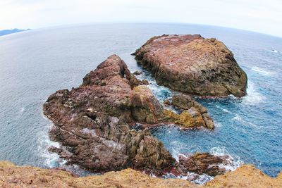 Rock formation on beach against sky