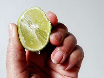 Close-up of hand holding strawberry over white background