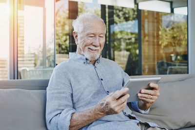 Senior man sitting on terrace reading ebook