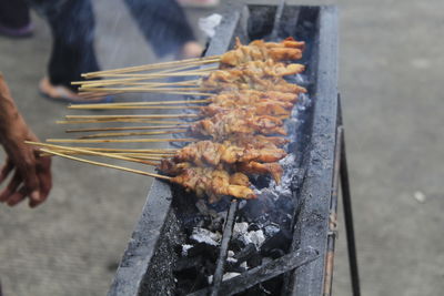 Cropped image of person preparing food on barbecue grill