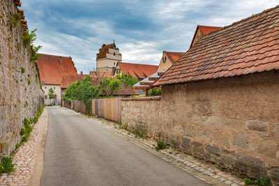 Road amidst houses against sky