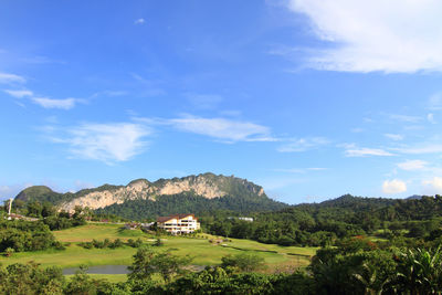 Scenic view of field by mountain against sky