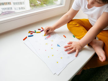 Midsection of woman writing in book at table