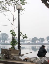 Rear view of man crouching on promenade by lake