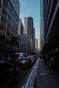 Vehicles on road amidst buildings in city against sky