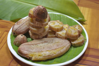 Grilled banana with dipping sauce on wooden table.