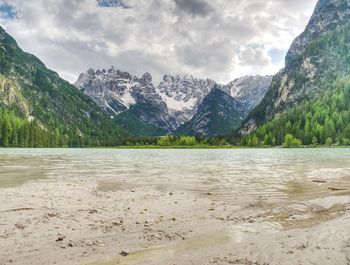 Blue green lake between sharp mountains. smooth water surface, the peaks are illuminated by the sun