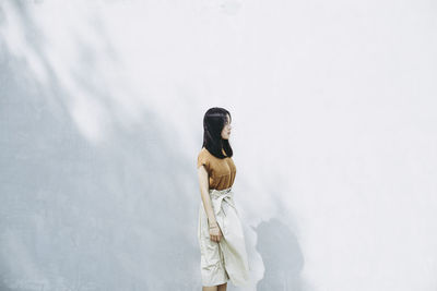 Woman standing against white wall