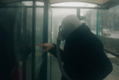 Side view of woman looking through window