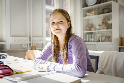 Portrait of smiling girl sitting at desk in classroom