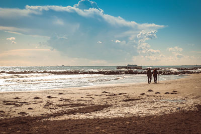 People standing on beach against sky