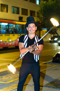 Portrait of cheerful man performing with fire on street at night