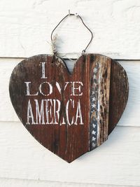 Close-up of wooden heart shape with text on wall