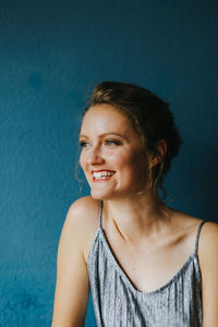 Portrait of smiling young woman against blue background