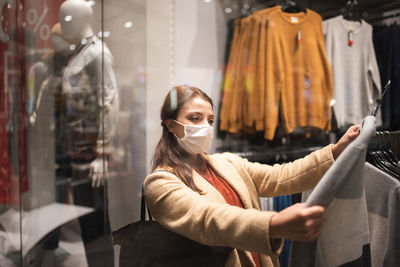 Woman wearing mask while looking at garments