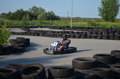 Man driving go-cart amidst tires on street