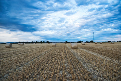 Hay bales on field against sky