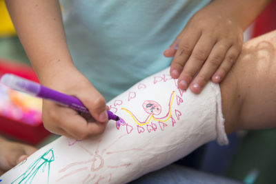 Little girls painting her mother's plaster arm