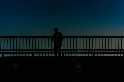 Silhouette man standing on bridge against sky