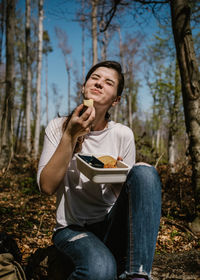 Happy woman eating food in forest
