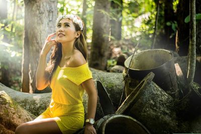 Young woman sitting against trees in forest