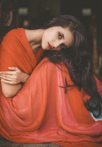 Portrait of beautiful young woman in red dress sitting at home