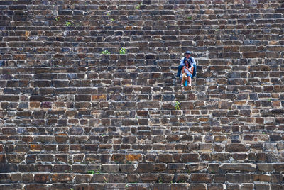 Low angle view of man against brick wall