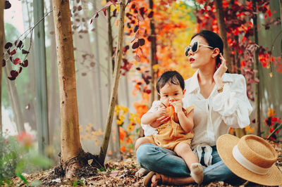 Mother and son sitting at forest during autumn