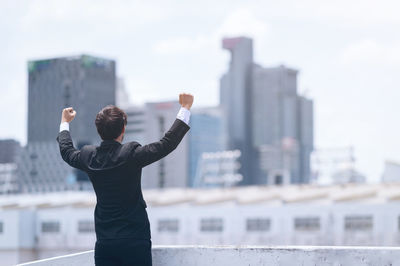 Rear view of man standing by cityscape against sky