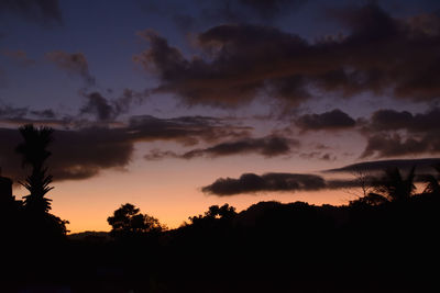 Low angle view of silhouette trees against dramatic sky