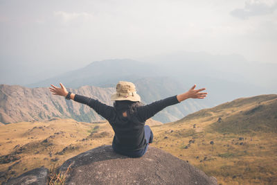 Full length of man with arms raised against mountain range