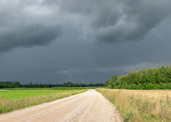 Road amidst field against sky