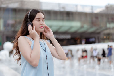 Woman looking away while standing on mobile phone