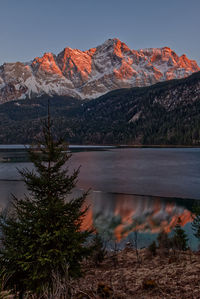 Scenic view of lake by mountains against sky at sunset