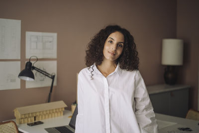 Portrait of young woman standing against wall