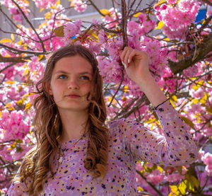 Portrait of young woman standing against tree