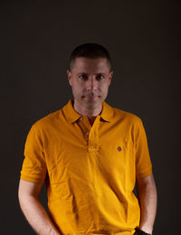 Portrait of young man standing against black background