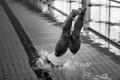 Low section of woman jumping in swimming pool