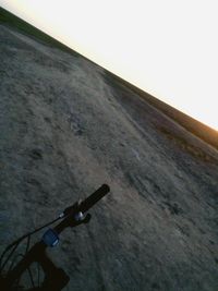 Cropped image of riding bicycle on road against sky